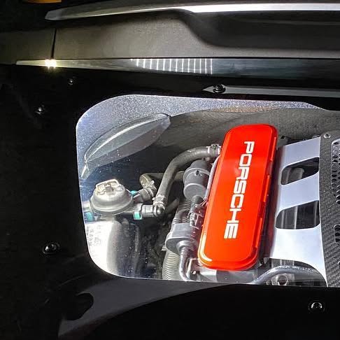 Porsche engine visible beneath an illuminated clear cover